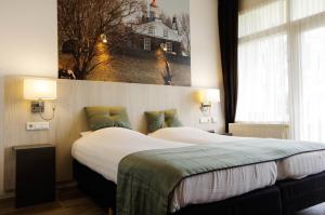 a hotel room with two beds and a picture on the wall at Hotel and Restaurant van Saaze in Kraggenburg