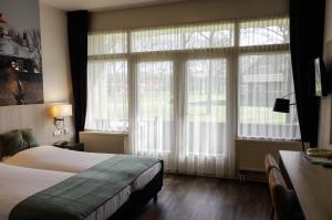 um quarto com uma cama e 2 janelas grandes em Hotel and Restaurant van Saaze em Kraggenburg