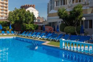 貝尼多姆的住宿－Magic Villa de Benidorm，一座带蓝色躺椅的游泳池,位于大楼旁