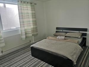 een slaapkamer met een bed en een raam bij White House "Luton Airport" in Luton