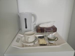 盧頓的住宿－White House "Luton Airport"，一个带两个杯子和咖啡壶的托盘