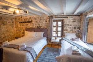 two beds in a room with stone walls at το σπίτι του δάσκαλου- teacher's house in Sirako