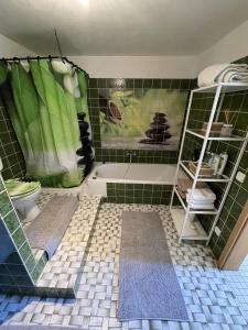 W łazience znajduje się wanna i wyłożona zielonymi kafelkami podłoga. w obiekcie Apartment Isenbügel / Essen-Kettwig w mieście Heiligenhaus