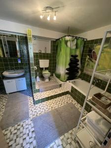 W wyłożonej zielonymi kafelkami łazience znajduje się wanna i umywalka. w obiekcie Apartment Isenbügel / Essen-Kettwig w mieście Heiligenhaus