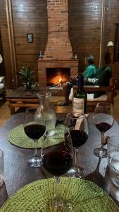 a table with glasses of wine and a fireplace at Pousada Recanto das Hortênsias in Cunha