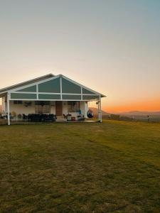 a house with a large green field with the sunset in the background at Tinton Hillstay in Chikmagalūr