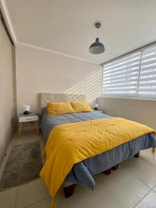 a bedroom with a bed with a yellow blanket at Cumbre de Reñaca II in Viña del Mar