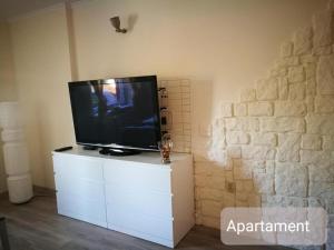 una TV a schermo piatto seduta su una cassettiera bianca di LuLu Apartamento Centro a Łagów