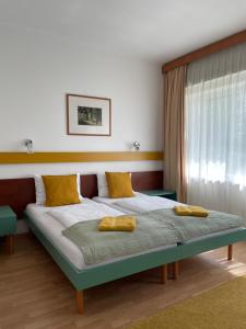 a bedroom with a bed with yellow pillows on it at Hello Balcsi Apartmanház in Tihany