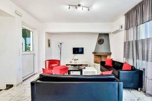 a living room with a black couch and red chairs at Villa Xenos Tria in Tigaki