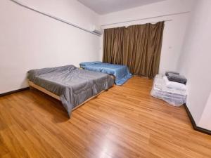 Cozy Party Homestay nearby Airport في سانداكان: غرفة نوم بسريرين في غرفة ذات أرضيات خشبية