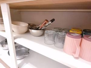 a kitchen shelf with bowls and other kitchen utensils at Cozy Party Homestay nearby Airport in Sandakan