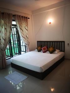 Bett in einem Zimmer mit einem großen Fenster in der Unterkunft Hotel Bird Paradise in Sigiriya