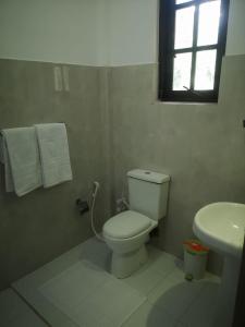 a white bathroom with a toilet and a sink at Hotel Bird Paradise in Sigiriya