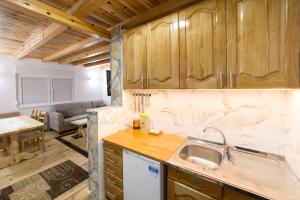 a kitchen with wooden cabinets and a living room at Stojanov Konak in Lazići