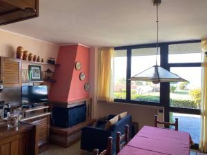 een woonkamer met een eettafel en een televisie bij Flowers and garden apartment in Manerba del Garda