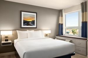 a bedroom with a large white bed and two windows at Microtel Inn & Suites by Wyndham Boisbriand in Sainte-Thérèse-de-Blainville