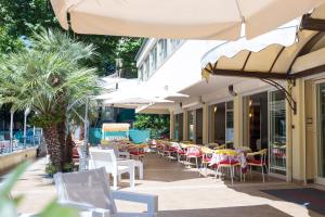 un patio al aire libre con mesas, sillas y sombrillas en Hotel Cavour, en Cesenatico