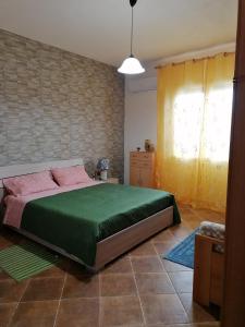 a bedroom with a green bed and a window at Casa Waida in Marinella di Selinunte