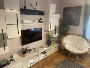 uma sala de estar com uma televisão num armário branco em Szemes Villa em Balatonszemes