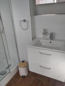 y baño blanco con lavabo y ducha. en Ferienwohnung-Hahnenstrasse, en Steinfurt