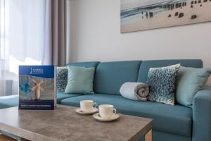 a living room with a blue couch and two cups on a table at Ambria Apartments Centrum in Świnoujście