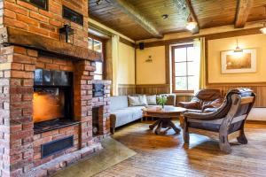 a living room with a couch and a fireplace at Klumpes Malunas in Vosbutai