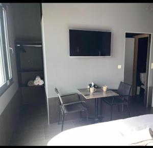 a room with a table and chairs and a television at Logements des choraux in Tournai