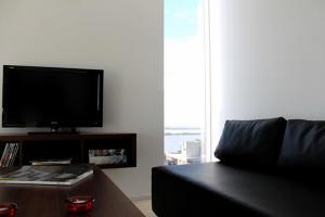 sala de estar con sofá negro y TV de pantalla plana en Altos de Maipu Rosario en Rosario