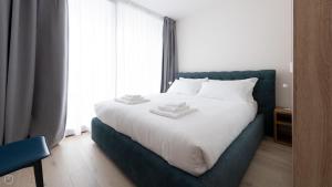 a bedroom with a white bed with a blue headboard at Dosso del Grillo 1A in Valdidentro