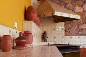 a kitchen with clay pots and vases on the wall at Casa Amarilla in Guanajuato