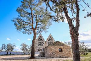 uma velha igreja de pedra com duas árvores em Casale Amendolagine em Terlizzi