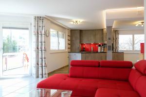 a living room with a red couch and a kitchen at Susy's Place in Spiez