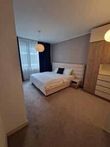 a bedroom with a white bed and a large window at Anvers Apartament in Bucharest