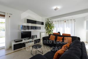 a living room with a couch and a tv at Blue Beach by ACasaDasCasas in Ericeira