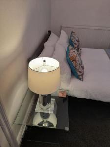 uma lâmpada numa mesa de vidro ao lado de uma cama em Fabulous terrace cottage em Blackpool