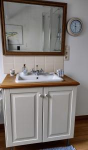 een badkamer met een witte wastafel en een spiegel bij L Heure Bleue in Wezembeek-Oppem
