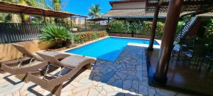 a swimming pool in a yard with chairs and a house at Pousada Villa D' Garden in Ribeirão Preto