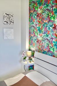 - une chambre avec un papier peint tropical et un lit avec une lampe dans l'établissement Viareggio Deluxe, à Viareggio