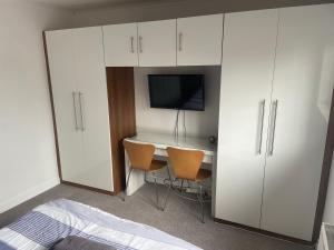 a bedroom with a desk and a tv and white cabinets at River View House St Neots - Navigation Wharf in Saint Neots