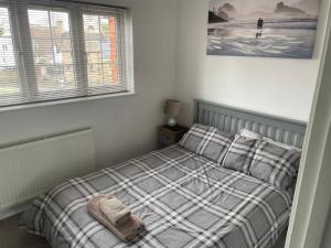 a bedroom with a bed with a plaid blanket and two windows at River View House St Neots - Navigation Wharf in Saint Neots