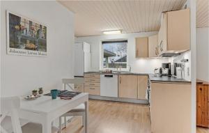 una cocina con electrodomésticos blancos, mesa y sillas en Beautiful Home In Skagen With Kitchen, en Skagen