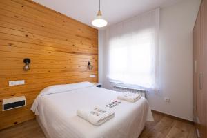1 dormitorio con cama blanca y pared de madera en CASA MARTA Garaje Gratis, en Zamora