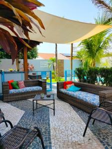 un patio con sofás, mesas y una sombrilla en Cambará Suítes, en Bonito
