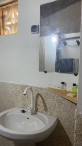 uma pessoa a tirar uma foto de um lavatório numa casa de banho em Petite maison en bord de mer em Palmarin Nguèdj