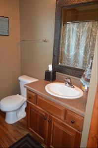 Un baño con lavabo, inodoro y espejo. en Bridges Bay Vacation Cabin 69, en Arnolds Park