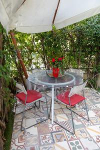 une table en verre avec deux chaises et un vase avec des roses dans l'établissement MERLO 2 mare & parking, à Viareggio