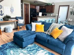 - un canapé bleu avec des oreillers jaunes dans le salon dans l'établissement Bridges Bay Vacation Cabin 126, à Arnolds Park