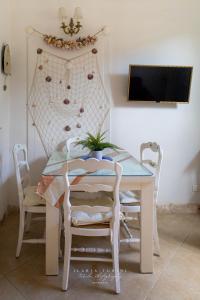 une table blanche avec des chaises et une télévision murale. dans l'établissement MERLO 2 mare & parking, à Viareggio