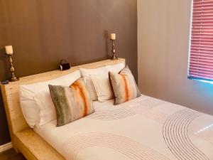 1 dormitorio con 1 cama con sábanas y almohadas blancas en Mo's Explorer Cape Town Vacation Apartment, en Ciudad del Cabo